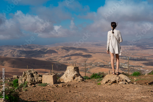 A woman looking towards the rocky, harsh mountains. View from Astronomical viewpoint Sicasumbre area in Fuerteventura island (Mirador De Morro Velosa, Spain)  photo
