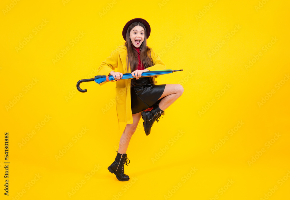 Fall fashion accessory, stylish girl isolated on yellow hold parasol. Excited teenager, glad amazed and overjoyed emotions. Child wuth umbrella under rain. Rainy weather, seasonal. Jump movement. Fall fashion accessory, stylish girl isolated on yellow hold parasol. Excited teenager, glad amazed and overjoyed emotions. Child wuth umbrella under rain. Rainy weather, seasonal. Jump movement.