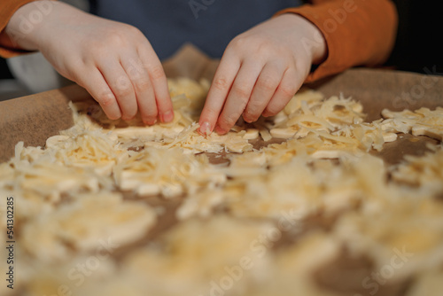 children's hands make cheese cookies on a metal tray with parchment