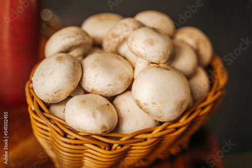 wicker basket with champignon mushrooms on a dark background