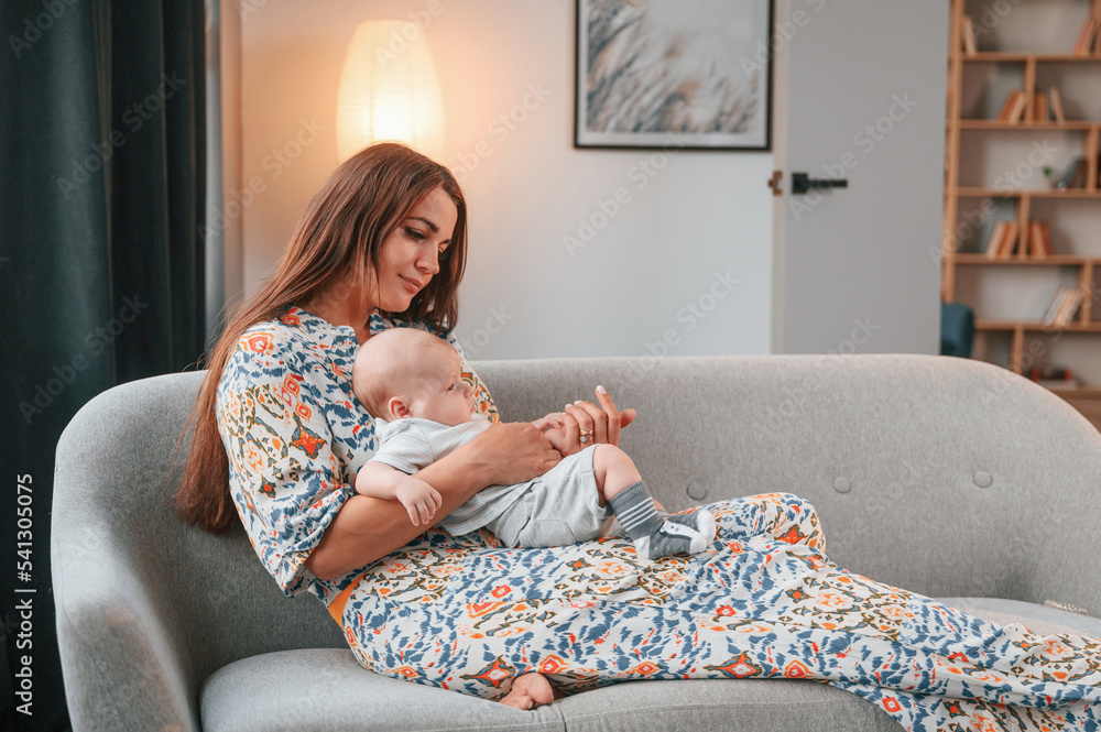 Laying down on the sofa. Beautiful happy mother with her newborn son is at home Laying down on the sofa. Beautiful happy mother with her newborn son is at home