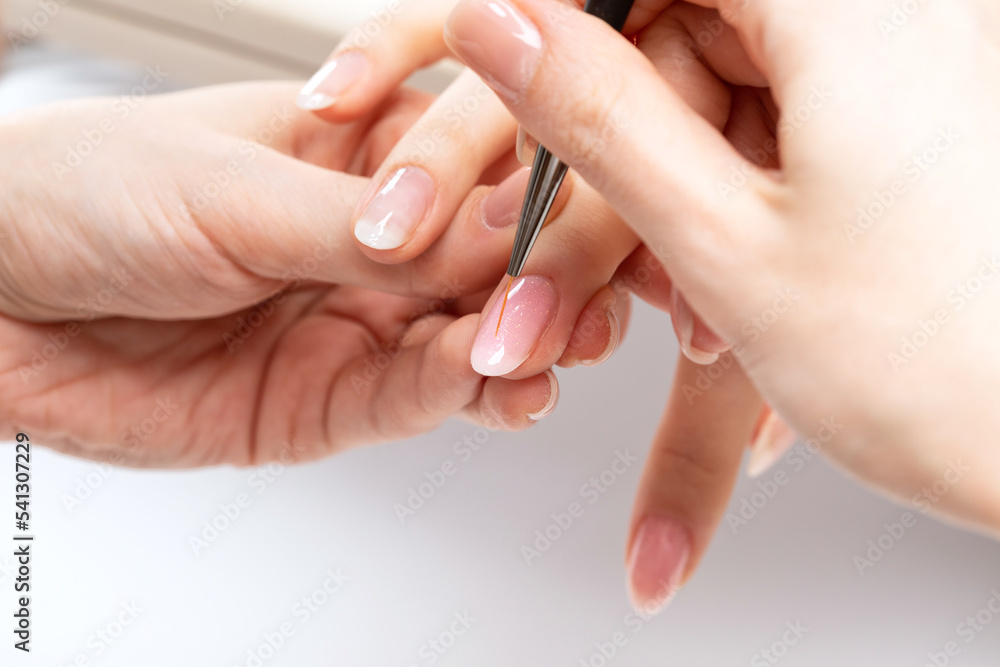 The master of the manicure coats nails with gel polish in the beauty salon. Professional care for hands. The master of the manicure coats nails with gel polish in the beauty salon. Professional care for hands.