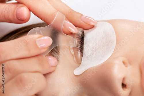 Make-up artist makes the procedure of lamination and dyeing of eyelashes to a beautiful woman in a beauty salon. Eyelash extensions. Eyelashes close-up