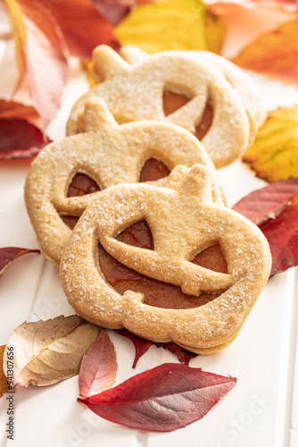 Linzer cookies in the shape of a Halloween pumpkin on white table.