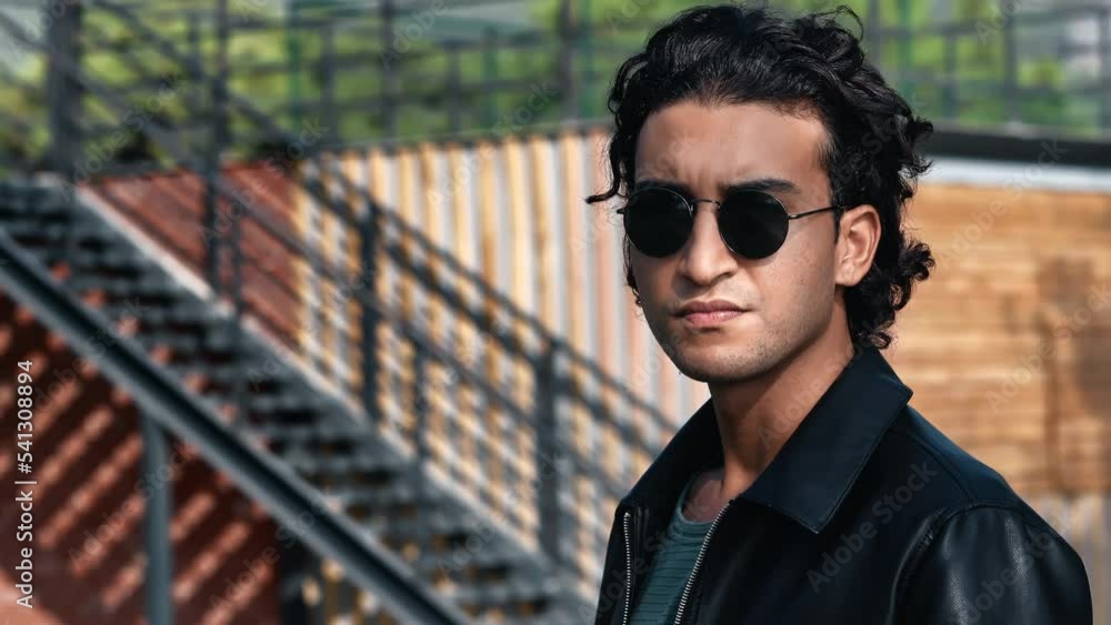 Brutal Latino curly man in sunglasses posing outdoor summer park wooden stairs construction closeup Brutal Latino curly man in sunglasses posing outdoor summer park wooden stairs construction closeup