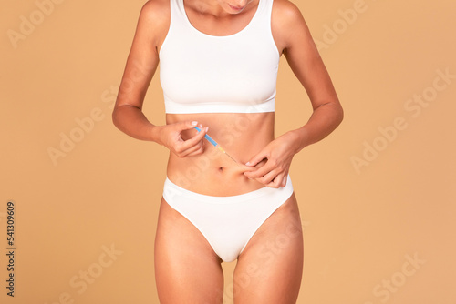 Принти на полотні Woman holding skin on stomach and injecting medicine from syringe, standing over