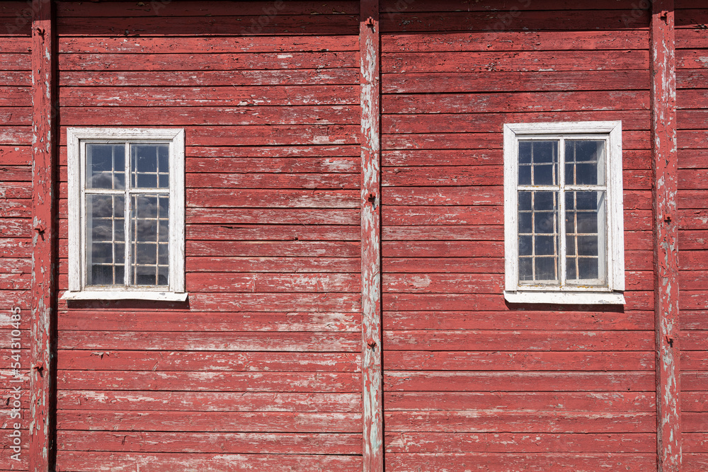 Facade of an old village house. Red wooden wall with windows. Facade of an old village house. Red wooden wall with windows.