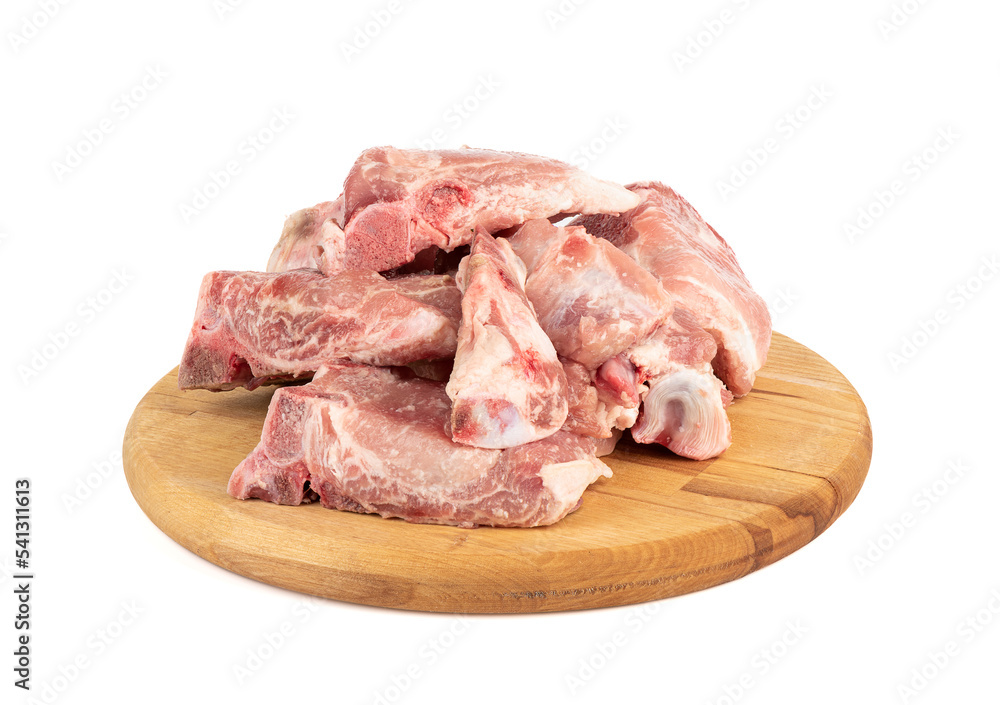 Pieces of pork stew on a round cutting board over a white background.