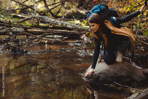 Fototapeta Naklejka Na Ścianę i Meble -  Woman Hiking in the Forest and her Hand Touching the cold River Water