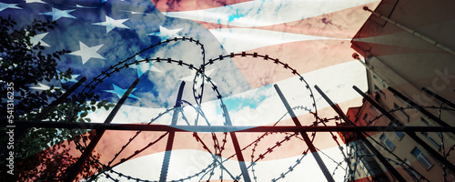 Usa flag overlay prison building with metal fence and barbed wire. Freedom and military concept.