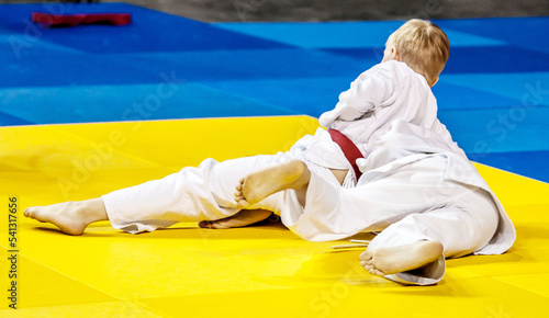 Two boys fighter judoka in judogi compete on the tatami 