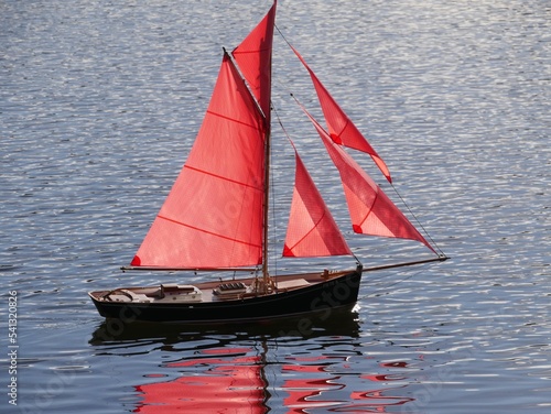 Modellschiff mit roten Segeln auf dem Wasser