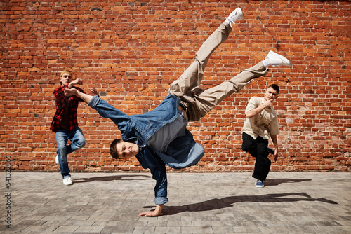 Fotografia, Obraz Freeze frame of male breakdance performer doing handstand pose with team against