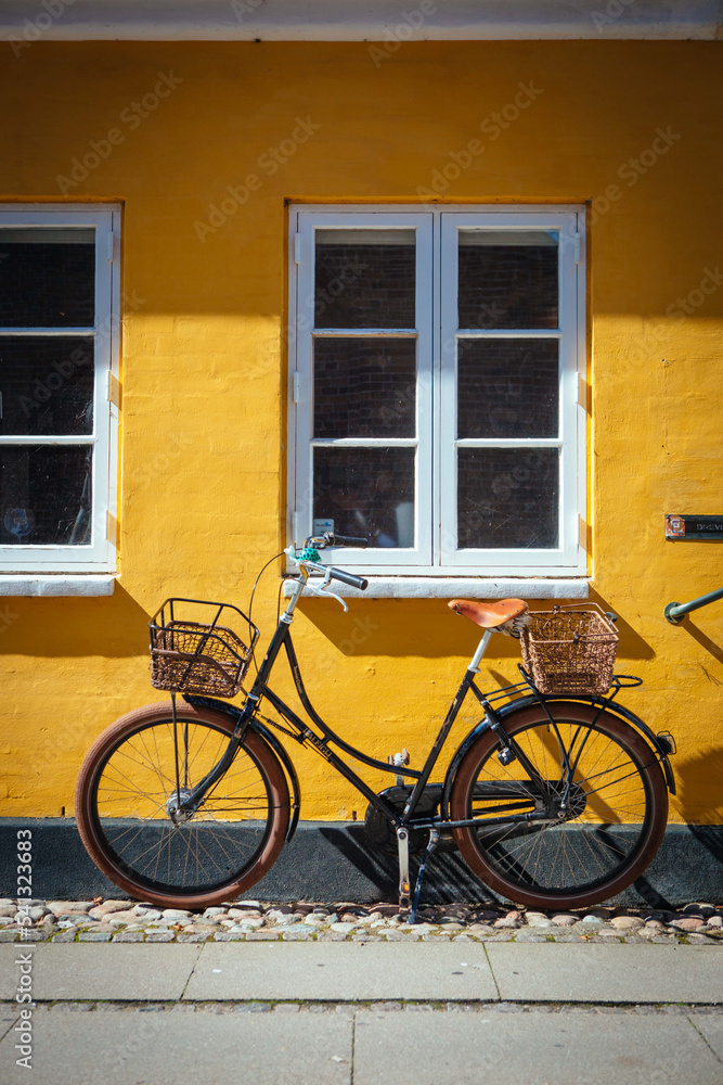 Fahrrad vor gelber Hauswand mit weißen Sprossenfenstern