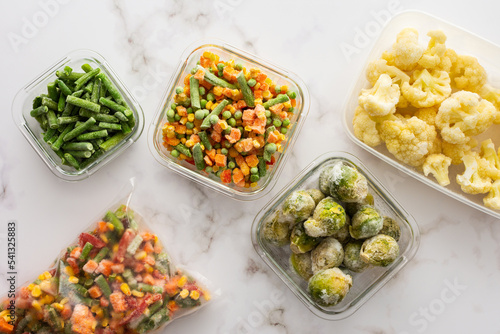Frozen vegetables in containers and bags, frozen cauliflower and asparagus beans, peas and corn, Brussels sprouts and carrots, mix of vegetables, top view, copy space