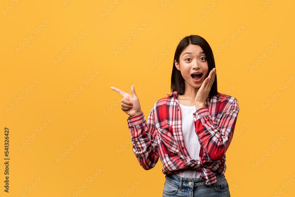 Wow, look at it. Overjoyed chinese lady pointing aside at empty space, demonstrating space for your design or ad text Wow, look at it. Overjoyed chinese lady pointing aside at empty space, demonstrating space for your design or ad text