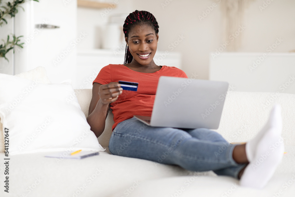 Smiling African American Female Making Online Payments With Laptop And Credit Card Smiling African American Female Making Online Payments With Laptop And Credit Card