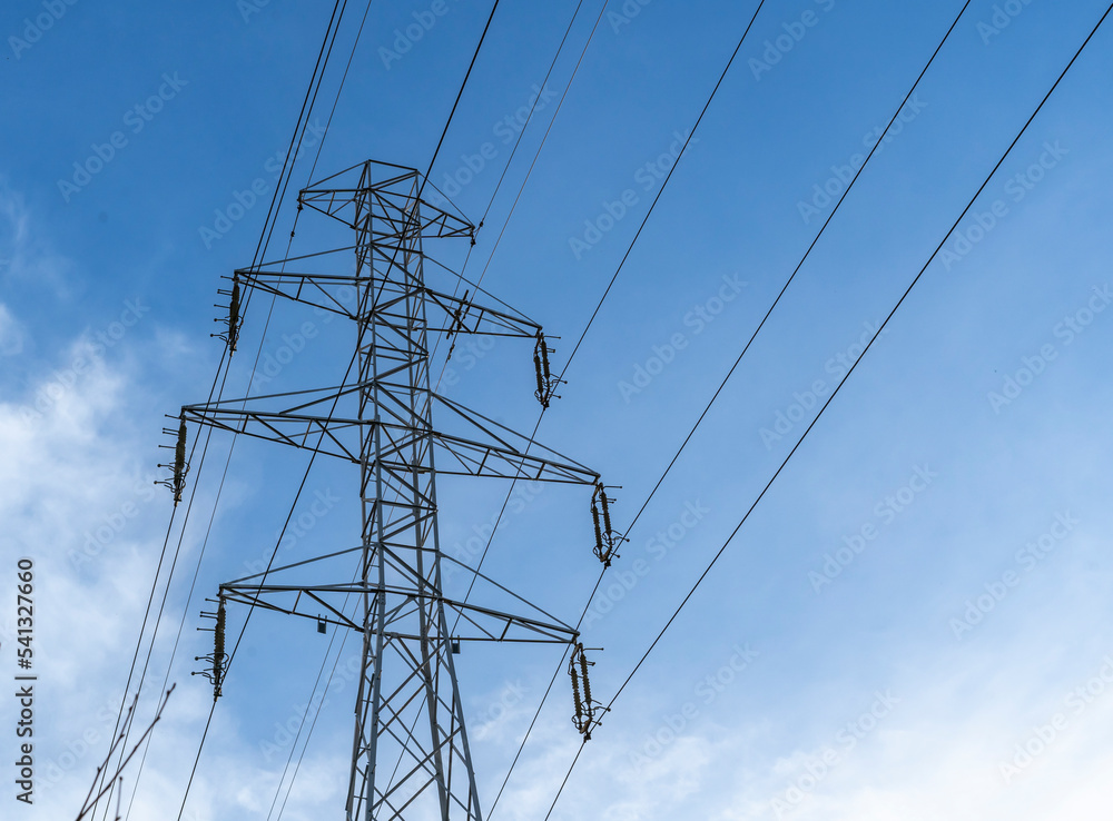 Electric station for supplying electricity to city, village. High voltage electric tower. Close-up. Power line against blue sky. Electric station for supplying electricity to city, village. High voltage electric tower. Close-up. Power line against blue sky.