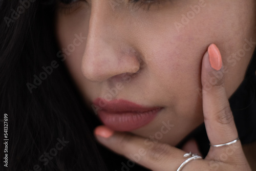 close up of a latina girl's face has rings on her fingers and her lips are full.