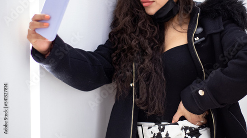 body and face of a Latina girl taking a selfie in a brightly lit aisle of a shopping mall.