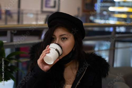 Pretty latina girl shopping in a mall, she has a coffee.