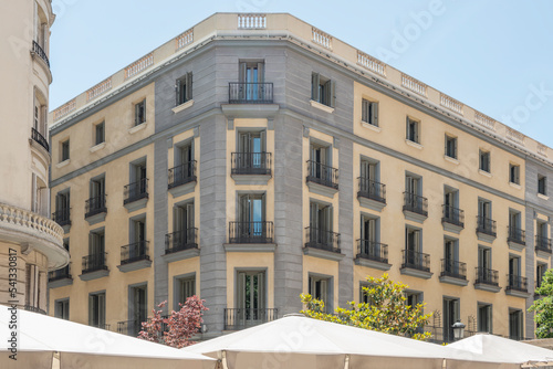 A central square of the city of Madrid with white awnings with many facades of urban residential buildings of old construction with a lot of stone and metal