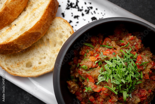 Baked eggplant caviar and vegetables with toast on a dark background