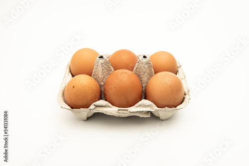 Half a dozen brown eggs in a container or egg cup