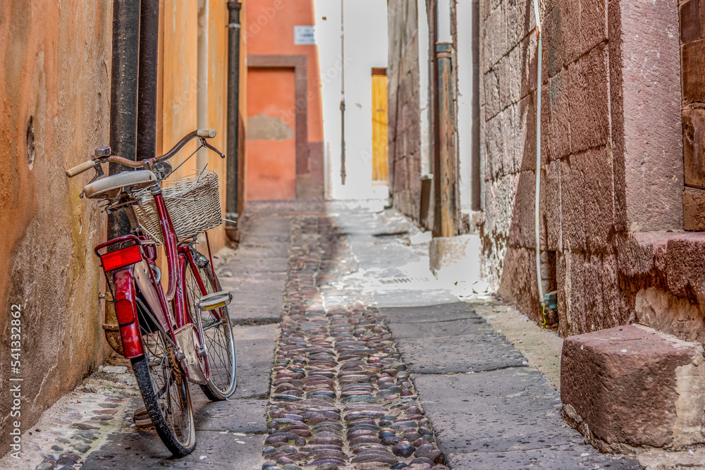 Old bicycle leaning against a wall in a narrow alley in old town Bosa