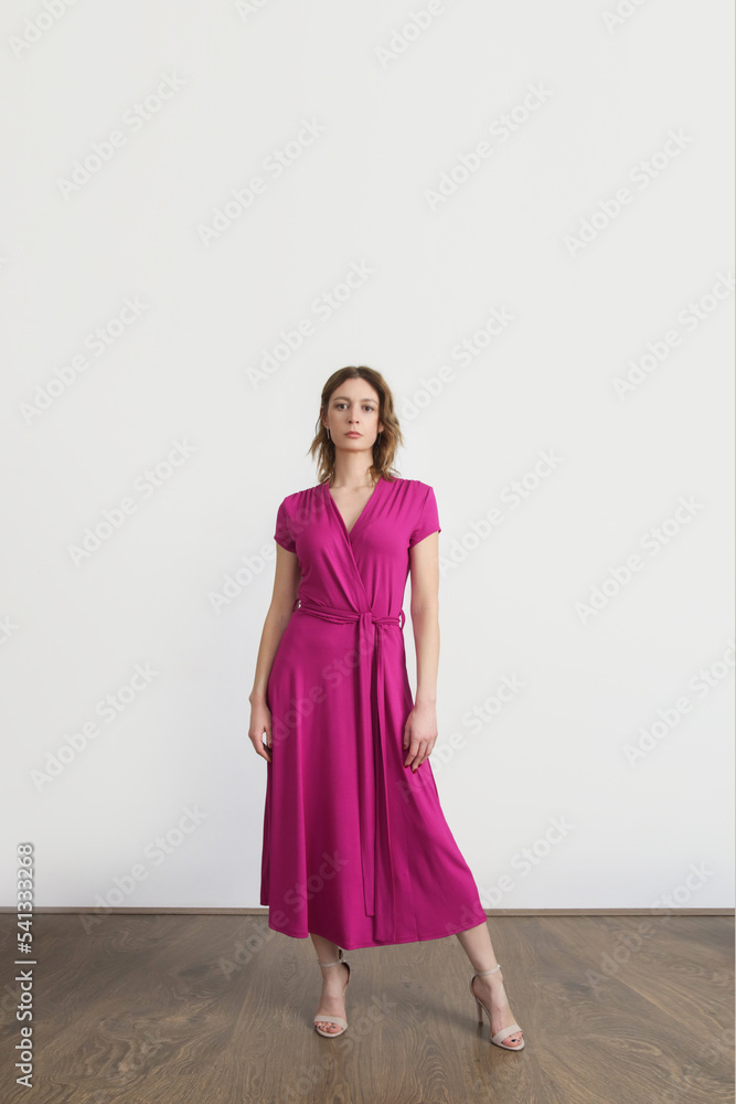 Serie of studio photos of young female model in bright pink wrap dress. Serie of studio photos of young female model in bright pink wrap dress.