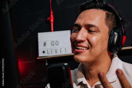 Host Talking and smiling on mic in a stream, podcast show, with headset (headphones) red and black background photo