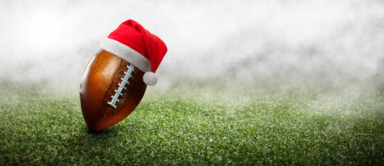 American football ball on the grass of a stadium with christmas hat