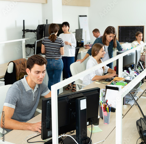 Positive glad people working with computers and laptops in modern office