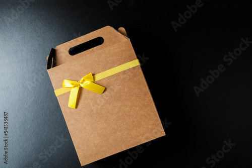 Gift wrapping with a yellow bow and black background. Seen from above. Copy space. Gift concept. Yellow bow concept.