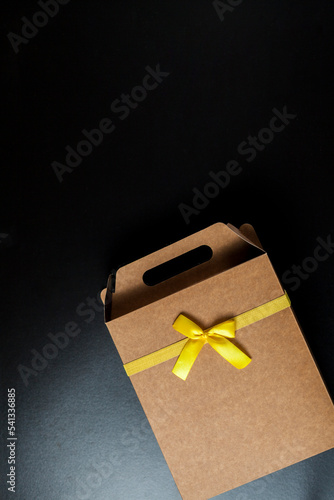 Gift wrapping with a yellow bow and black background. Seen from above. Copy space. Gift concept. Yellow bow concept.