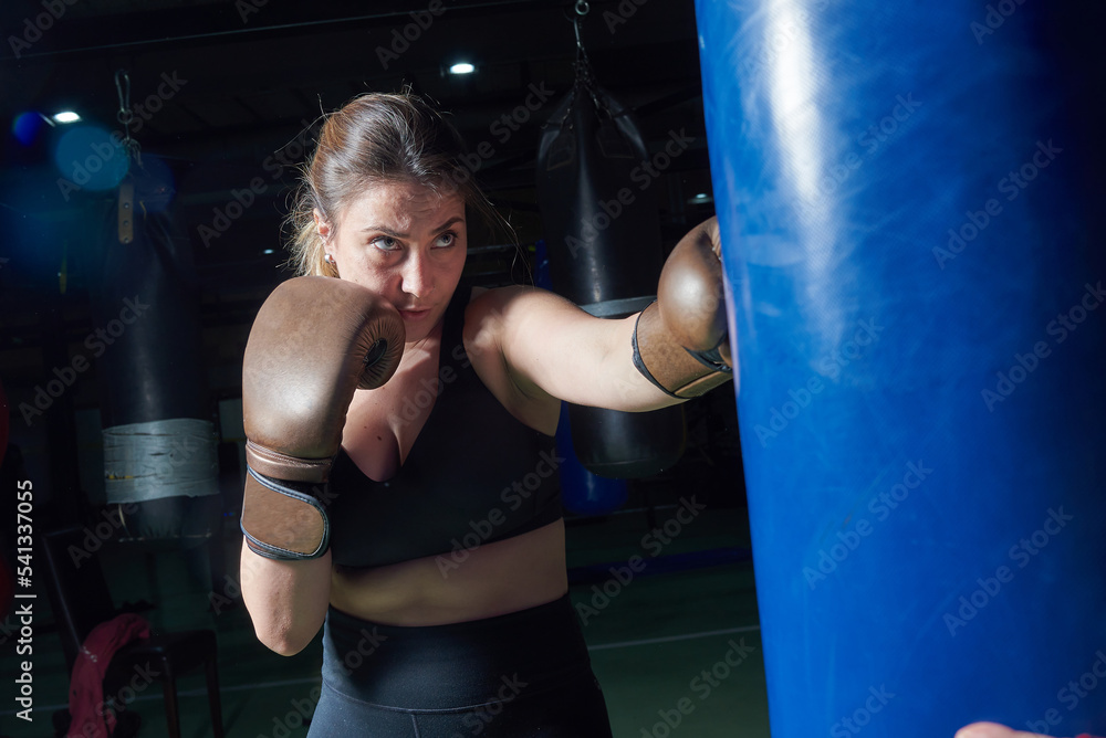 Young fit woman punching a boxing bag at the gym