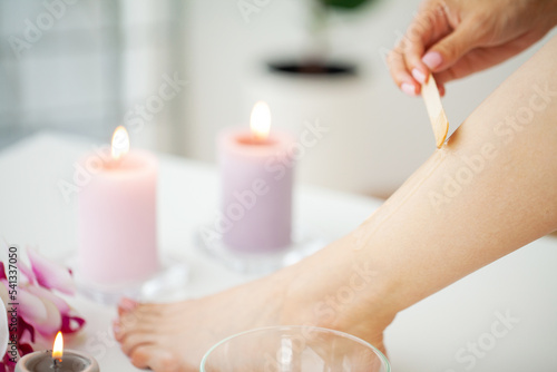 Woman applies wax to her leg to remove hair