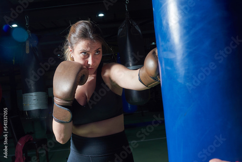 Young fit woman punching a boxing bag at the gym