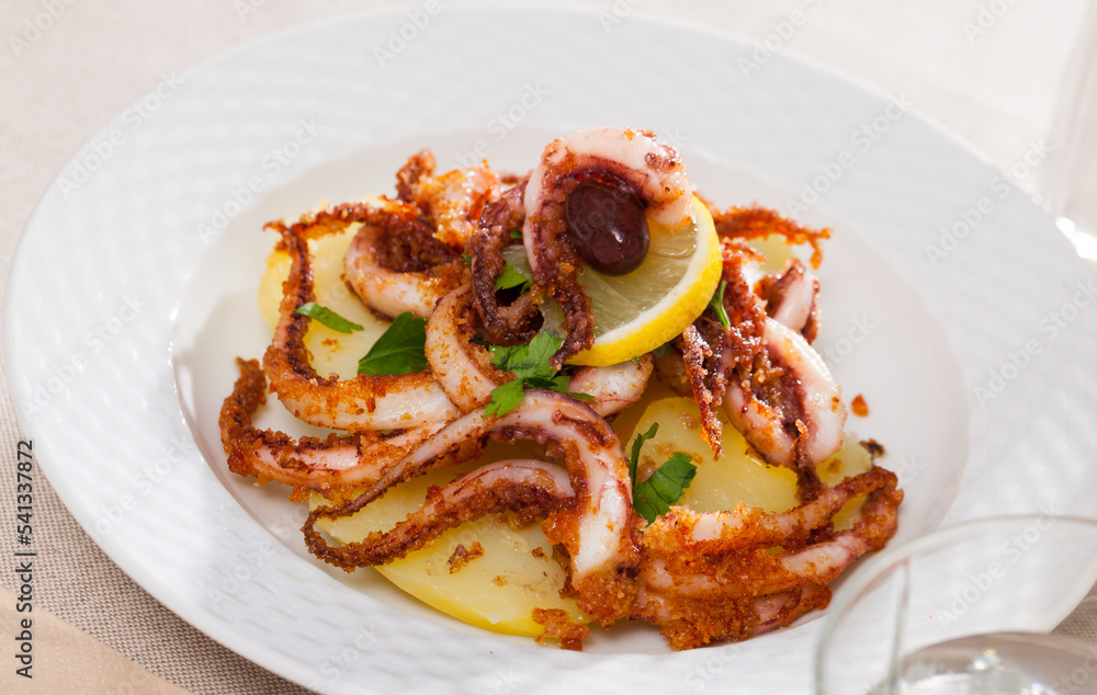 Dish of Mediterranean cuisine - roasted squid legs with lemon and parsley