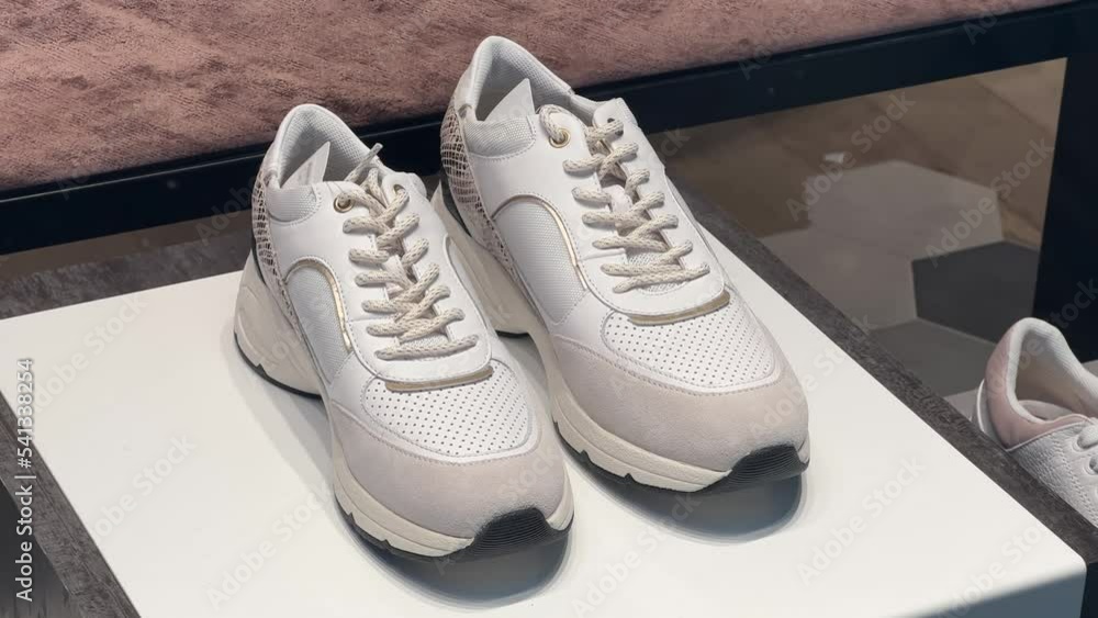 White casual sneakers with mesh stand in the window of a shoe store White casual sneakers with mesh stand in the window of a shoe store