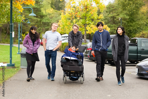 Multiracial group walking at park with child in wheelchair