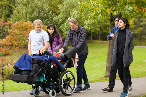 Multiracial group walking at park with child in wheelchair
