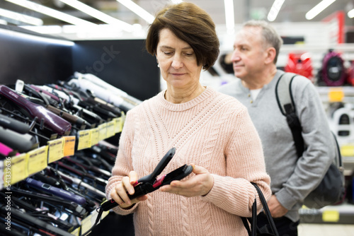 Portrait of a European woman choosing an electric styler near the shelves with goods in an electronics and household .appliances store photo