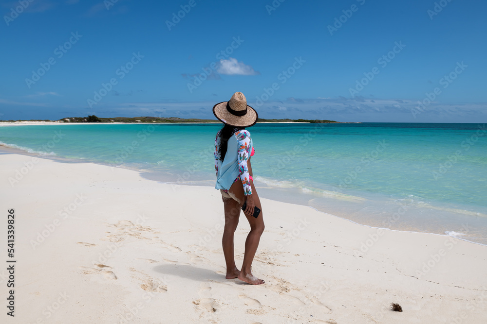 Cayo de Agua (Los Roques Archipelago), Venezuela, 07.30.2022: a young woman in the white beach with crystalline water.
