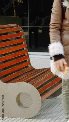 mujer sentada en un banco con el telefono en la mano	