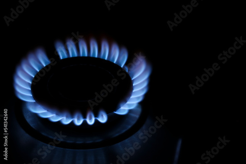 Gas cooktop with burning flame in darkness, closeup. Space for text © New Africa