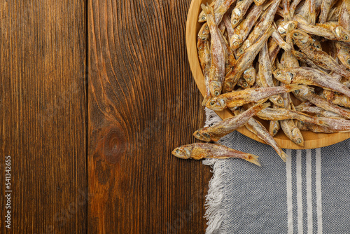 Tasty dried anchovies on wooden table, top view. Space for text