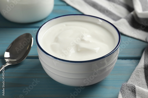 Bowl of tasty yogurt on light blue wooden table