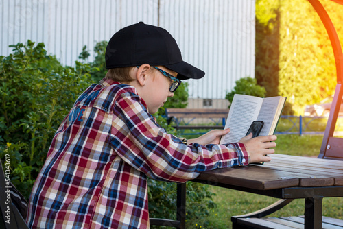 A teenager reads a book and plays on the phone on the street, surfs the Internet. Modern world.