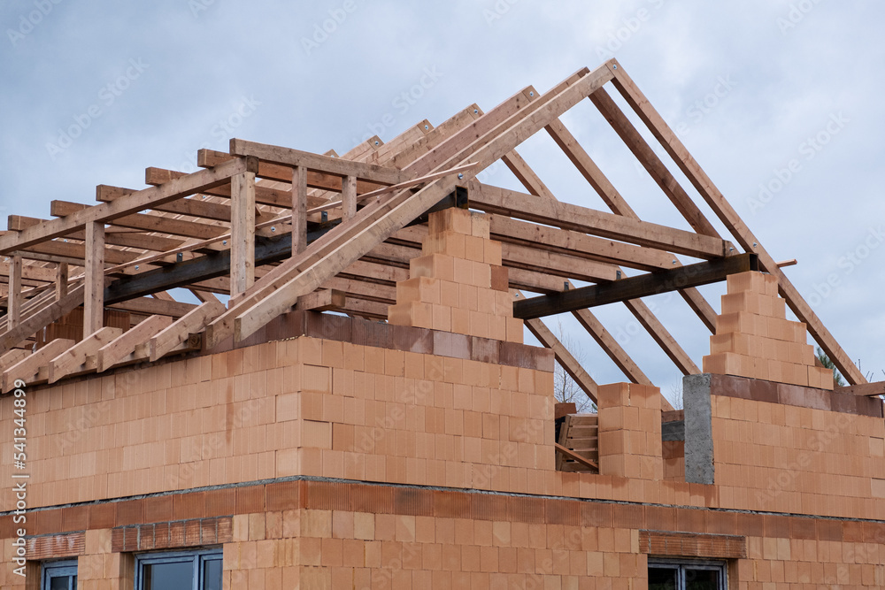 Roof construction on New Ceramic brick wall, the beginning of the wooden base for roof, wooden and metal log. Building work , house from ceramic blocks. Roof construction on New Ceramic brick wall, the beginning of the wooden base for roof, wooden and metal log. Building work , house from ceramic blocks.